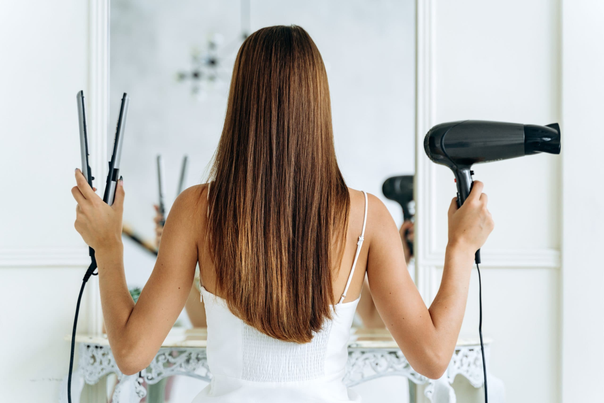 femme tenant un sèche cheveux et un lisseur